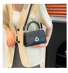 Détail d'un sac à main noir à paillettes avec fermoir cœur argenté et texture lisse
