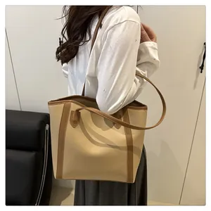 Detail shot of elegant beige tote bag with brown contrast trim on model's shoulder