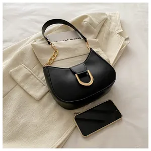 Close-up of black crescent shoulder bag with golden chain and metallic buckle detail