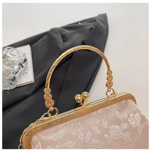 Détail du sac brodé de fleurs champagne avec cadre en métal doré gravé et fermoir à baiser