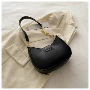 Detail of a black crescent shoulder bag with golden chain and square metal buckle clasp