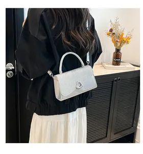 Détail d'un sac à main argenté à paillettes avec boucle coeur sur un mannequin