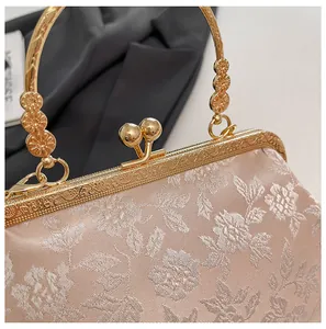 Détail de broderie florale sur satin avec cadre en métal doré orné et fermoir kiss lock