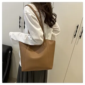 Close-up of brown matte PU leather tote bag with vertical stitching and long shoulder straps