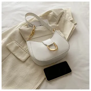 Macro view of white half-moon underarm bag with gold metal buckle and smartphone for size