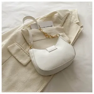 Detailed close-up of white crescent hobo bag with gold chain strap on beige blazer