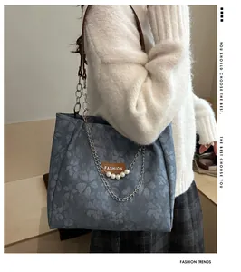 Detail view of light blue floral tote bag with elegant pearl chain and fashion label
