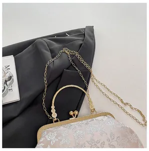Détail de la broderie florale vintage et du fermoir doré à boules sur le sac à main chinois