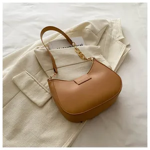 Detail of tan crescent shoulder bag with elegant gold chain and smooth leather texture
