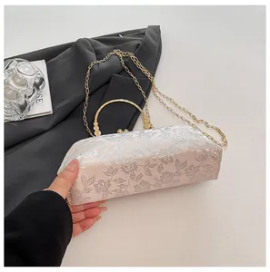 Détails d'un sac brodé avec poignée anneau dorée et bandoulière en chaîne métallique