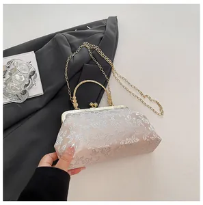 Détail d'un sac de soirée vintage en soie dorée avec broderie florale et chaîne