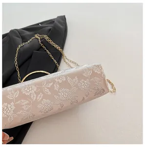 Détail du tissu brodé floral beige avec poignée dorée et chaîne en métal du sac chic