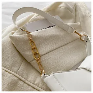 Close-up of white leather shoulder bag featuring a chunky gold chain strap detail