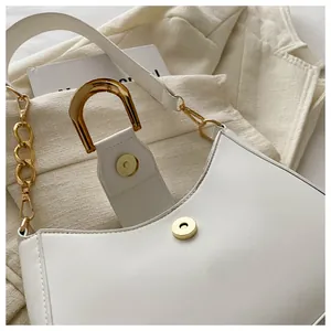 Detailed macro view of white crescent bag showing golden buckle and smooth leather texture