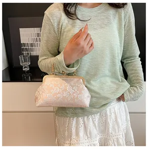 Détail du tissu brodé de fleurs vintage et du fermoir sphérique doré sur le sac à main