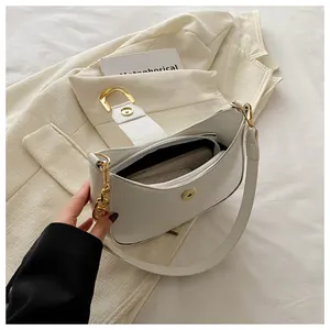 Macro view of white leather crescent bag with golden D-ring and magnetic closure