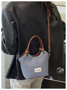 Détail d'un sac seau bleu texturé avec bandoulière en cuir porté par un modèle