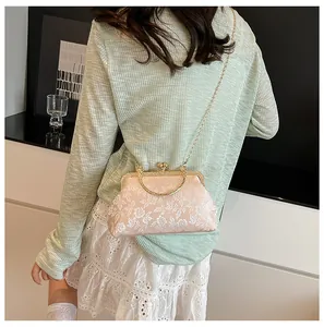 Détail du sac à main rose brodé de fleurs avec chaîne en métal doré et poignée vintage