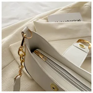 Detail of white minimalist shoulder bag with gold hardware and secure magnetic closure