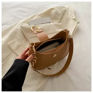 Detail view of khaki leather shoulder bag with magnetic clasp and gold chain accessory