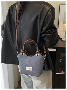 Détail du sac cabas en denim bleu et cuir marron montrant la bandoulière et la texture