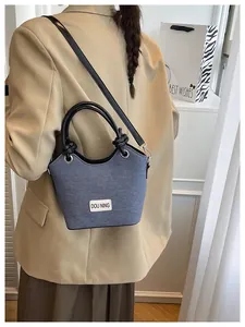 Détail du sac seau en denim avec bandoulière en cuir porté comme un sac à bandoulière chic