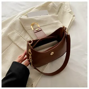 Detail of a dark brown half-moon bag featuring a large gold D-clasp and inner zip pocket