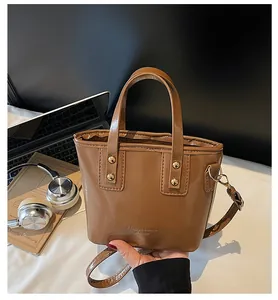 Piccola borsa marrone a tracolla con borchie dorate su una scrivania stile lifestyle