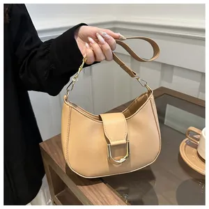 Detailed close-up of a cream crescent shoulder bag with a gold D-buckle and chain strap