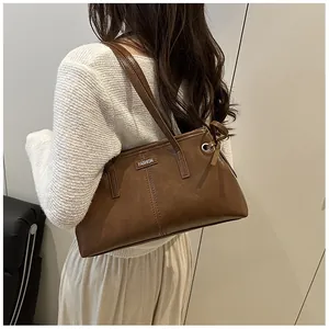 Detalle de un bolso tote de cuero sintético marrón con costuras verticales y etiqueta FASHION