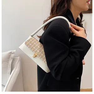 Close-up of white leather tweed handbag with gold rotary lock worn by a model
