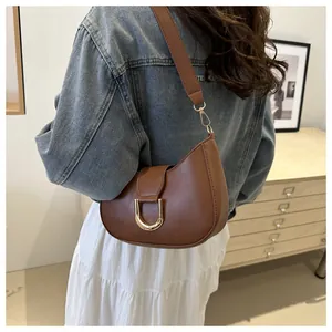 Detail view of a vintage brown leather underarm bag with gold metal buckle on a model