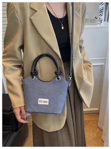 Détail du sac seau en tweed gris avec poignée ronde noire et étiquette de marque