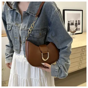 Detail view of brown leather crescent bag with golden horseshoe buckle and chain strap
