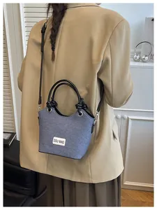 Détail du sac seau en tissu bleu avec poignées en cuir et étiquette décorative