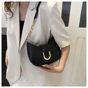 Detail of black leather half-moon bag featuring large gold horseshoe buckle and chain strap