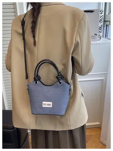 Vue détaillée du sac seau en denim bleu avec anses noires et écusson en cuir