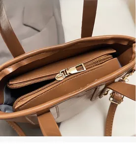 Dettaglio della cerniera in metallo dorato e trama in pelle marrone della borsa a secchiello