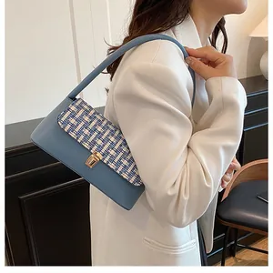 Detail of light blue leather shoulder bag with tweed flap and gold metal square buckle