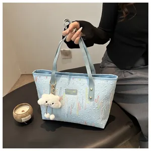 Detail of light blue tote bag featuring geometric embossed texture and plush cloud charm