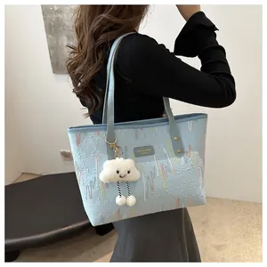 Detail of light blue tote bag with embossed textures and a cute plush cloud charm accessory