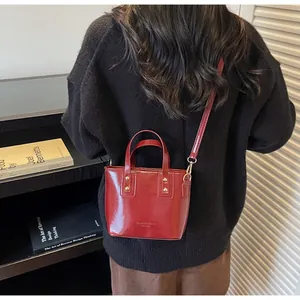 Borsa a tracolla bordeaux lucido con borchie dorate e tracolla regolabile per donna elegante