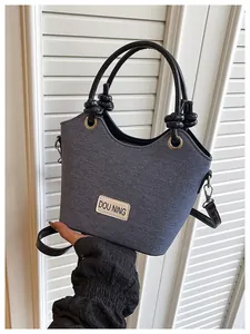 Vue macro détaillée du sac seau en denim bleu foncé avec étiquette de marque et anse en cuir