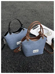 Détail du sac seau en texture denim avec poignées en cuir et finitions métalliques