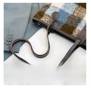 Detail view of plaid wool tote bag showing leather handles and FASHION logo tag