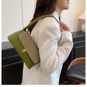 Detail of green leather and tweed patchwork shoulder bag with gold metal clasp lock
