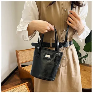 On-body shot of a black vintage bucket bag in oil wax leather with silver hardware
