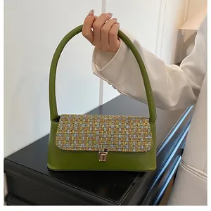 Detail of green leather underarm bag with colorful woven flap and gold metal buckle