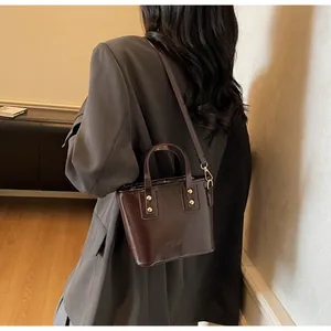Dettaglio mini tote in pelle lucida testa di moro con finiture dorate e tracolla sottile