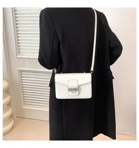 Detailed side view of white crossbody bag with diamond quilted texture and silver ring buckle